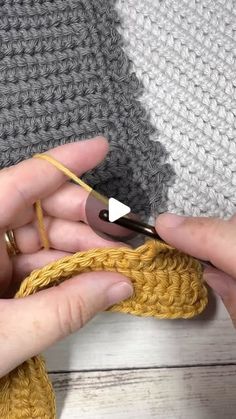 someone crocheting the end of a piece of fabric with scissors and yarn in their hands