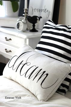 two pillows with black and white stripes on them, one has the word dream in cursive writing