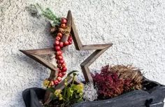 a wooden star hanging on the side of a building next to flowers and other decorations