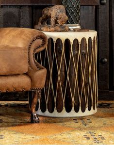 a brown chair sitting next to a table with a vase on it and a dog statue