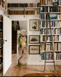 an old woman sitting on the floor in front of a bookshelf filled with books