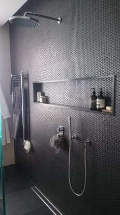 a bathroom with a shower head, shelves and towel racks on the wall next to it