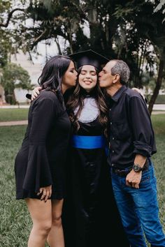 three people are posing for a photo while wearing graduation gowns and holding onto each other's shoulders