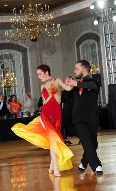 two people dancing on a dance floor with chandeliers in the background