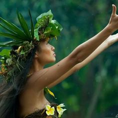 a woman with flowers on her head is holding out her arms to the side while wearing a flower crown