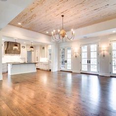 an empty living room with wood floors and chandelier