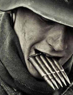 a man with a hat and bow tie biting into a piece of metal on his face