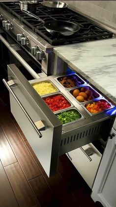 an open drawer in the middle of a kitchen counter with food inside and on it's side