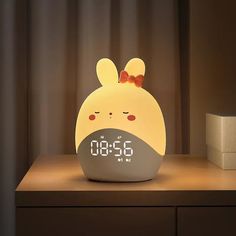 an alarm clock is sitting on a table next to a night light that looks like a bunny