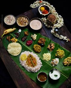 a large banana leaf filled with different types of food on top of a wooden table