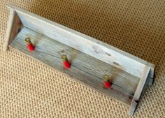 a wooden coat rack with red knobs on the front and back ends, sitting on a carpeted floor