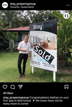 a man standing next to a sold sign