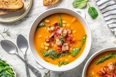 two bowls of soup with bacon, spinach and bread on the side next to each other