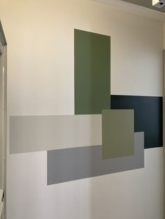 the wall is painted with different shades of grey and green squares on it, along with a white door