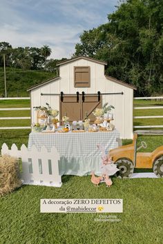 an outdoor table set up in front of a barn with hay bales and farm animals