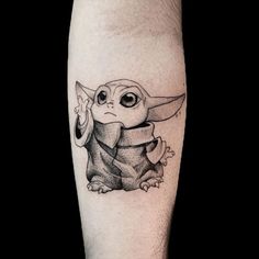 a black and white photo of a baby yoda tattoo on the leg