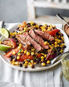 a white plate topped with meat and vegetables next to a bowl of sauce on top of a table