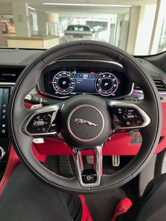 the interior of a car with red and black trims, steering wheel, dash lights, gauges and dashboard