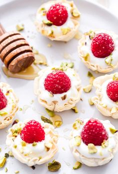 small desserts with raspberries, whipped cream and honey on a white plate