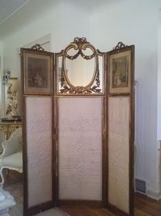 an ornate room divider with three mirrors on it's sides and two framed pictures