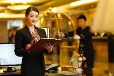 a woman standing in front of a desk holding a binder