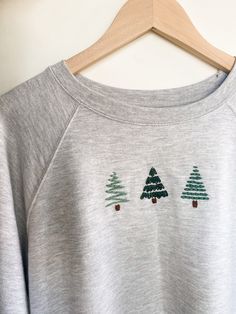 a grey sweatshirt with trees embroidered on it