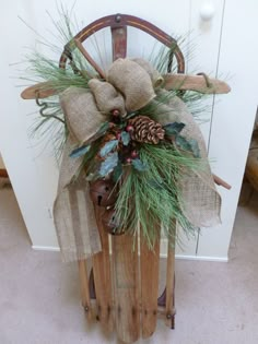 a wooden sled with pine cones, evergreen and burlocks tied to it