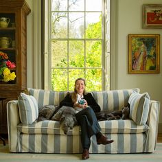 a woman sitting on a striped couch in front of a window