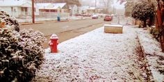 a red fire hydrant sitting on the side of a road covered in snow