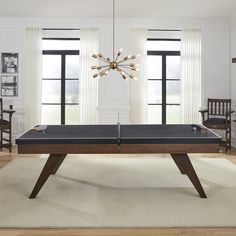 a ping pong table in the middle of a room with two chairs and a chandelier