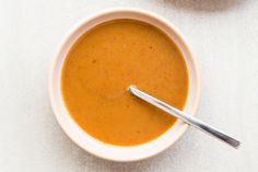 a bowl of soup with a spoon in it on a white tablecloth next to two bowls of soup