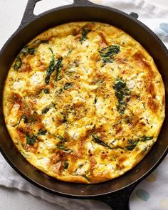 an omelet with spinach and cheese in a skillet on a table