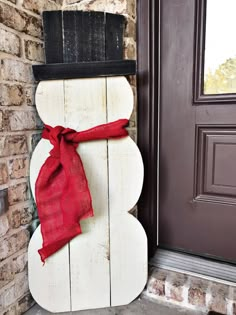 a snowman made out of pallet wood with a red scarf tied around it