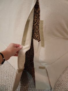 a person is opening the back of a white jacket with a brown tie on it