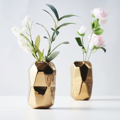 two gold vases with flowers in them