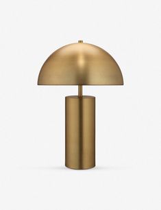 a gold table lamp on a white surface with a light bulb in the shape of a mushroom