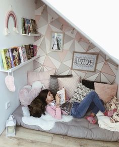 a woman laying on top of a bed next to a book shelf filled with books