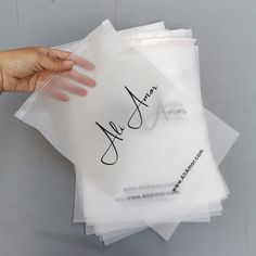 a hand is holding some clear envelopes with the word alger written on them