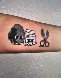 a person with a tattoo on their arm has scissors and a rock next to it