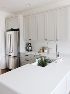 a kitchen with white counter tops and stainless steel refrigerator freezer next to an island