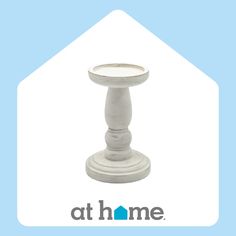 a white candle holder sitting on top of a blue and white house with the words at home above it