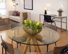 a living room filled with furniture and a round glass table topped with yellow flower centerpiece