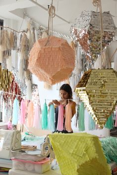 a woman standing in front of a table filled with lots of different colored paper decorations