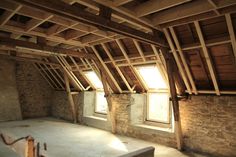 an unfinished room with exposed wooden beams and windows