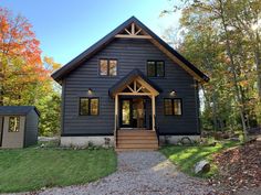 a black house with lots of windows in the front yard and stairs leading up to it