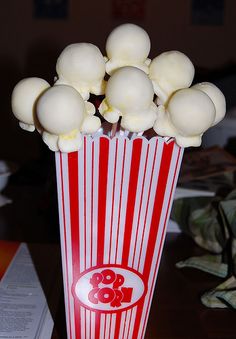 a red and white striped popcorn bag with marshmallows in it sitting on a table