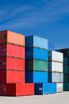 several multicolored shipping containers stacked on top of each other in front of a blue sky