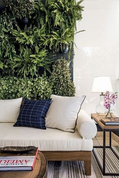 a living room with a couch, coffee table and green plant on the wall behind it