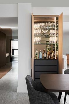 a dining room table and chairs with wine glasses on the top shelf in front of it