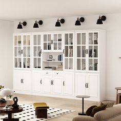 a living room filled with furniture and lots of white cupboards next to a black and white checkered rug